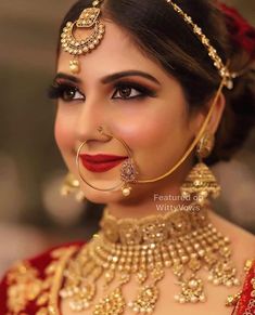 a woman wearing gold jewelry and red lipstick with her nose ring in the middle of her face