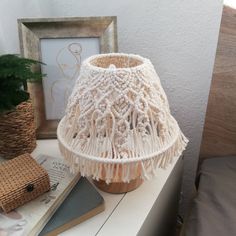 a white lamp shade sitting on top of a table next to a potted plant