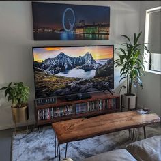 a flat screen tv sitting on top of a wooden table in a living room next to a window