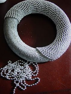 a beaded necklace sitting on top of a wooden table next to a white vase