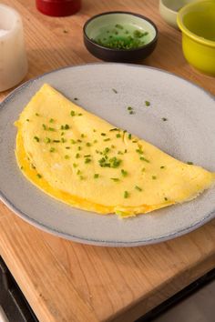 an omelet is sitting on a plate next to some bowls and spoons