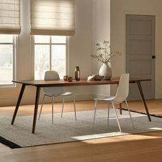 a dining room table with two chairs and a vase on the table next to it