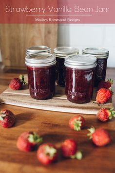 three jars of strawberry vanilla bean jam on a cutting board with strawberries around them