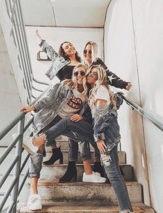 four girls are posing on the stairs in denim jackets and jeans with their arms around each other