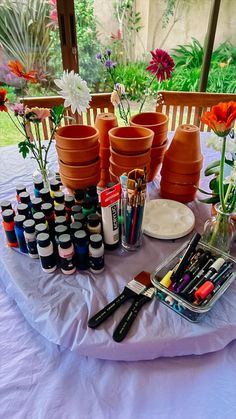 the table is set up with flowers and art supplies on it, including paint bottles