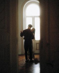 a man and woman standing in front of an open door with sunlight coming through the window