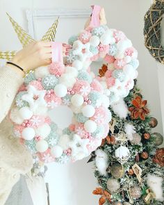 a woman is holding up a pink and white wreath