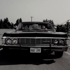 two people driving in the back of an old car