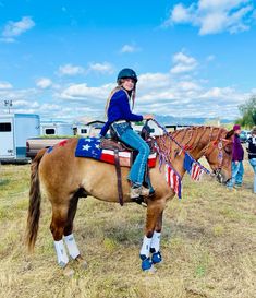 a woman riding on the back of a brown horse with an american flag decoration on it