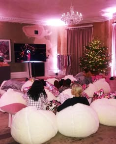 two children sitting on bean bags in a living room with christmas tree and pink lights