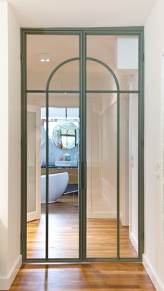 an open door leading to a bathroom with a bathtub in the background and wooden floors