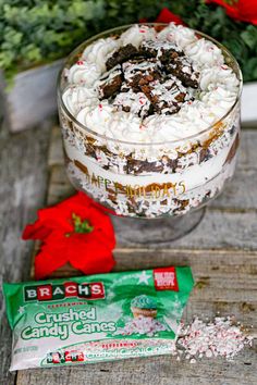 a close up of a dessert in a glass bowl on a wooden table next to a candy bar