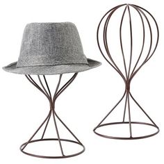 two metal hats sitting on top of stands next to each other, one with a hat on it's head