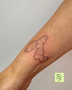 a person's arm with a small tattoo of a croissant on it