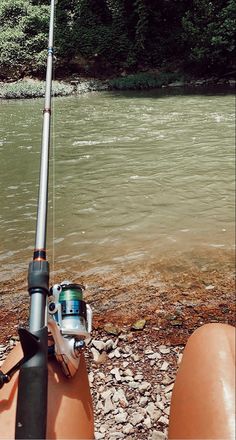 someone is sitting on the shore with their fishing rod