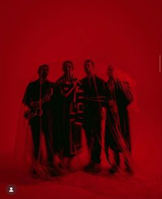 four people standing in front of a red background