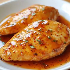 two pieces of chicken covered in sauce on a white plate