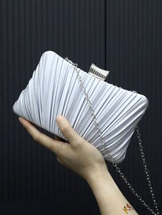 a hand holding a white purse with chain around it