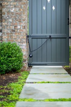 the front door to a home with green grass and bushes around it is painted gray