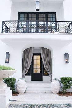 a large white house with black doors and two vases on the front steps next to it