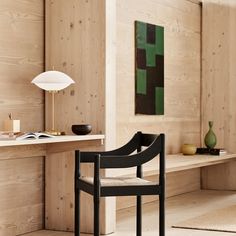 a chair sitting in front of a desk with a lamp on top of it next to a book shelf