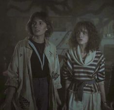 three young women standing next to each other in a dark room with one woman looking at the camera