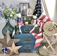 an old suitcase is filled with patriotic items and flowers in vases on the table