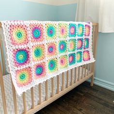 a crocheted blanket hanging from the side of a crib