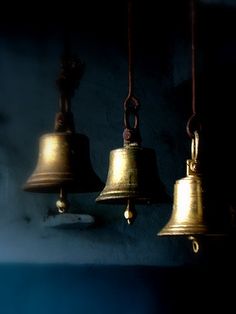 three bells hanging from the ceiling in front of a dark background with words written below them