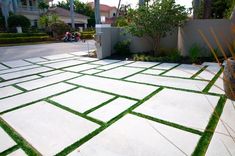 an outdoor patio with grass and plants in the center, surrounded by concrete blocks that have been cut into squares