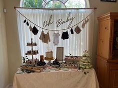 a baby shower is set up in front of a window with an assortment of desserts on it