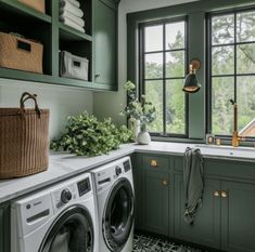 a washer and dryer in a small room with green cabinetry, windows, and tile flooring