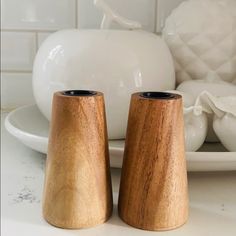 two wooden salt and pepper shakers sitting on a white plate next to a vase