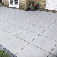 a cement patio in front of a brick house with potted plants on the side