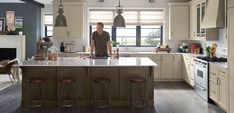 a man standing in the middle of a kitchen with an island and bar stools