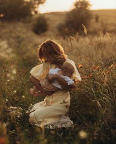 two children are playing in the grass with each other and one is holding an infant