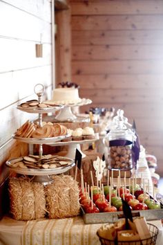 an assortment of desserts and pastries are displayed on a buffet table with straw bales