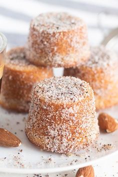 some almonds are on a white plate and there is a cup of tea next to them