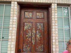 a woman standing in front of a wooden door with decorative designs on it's side