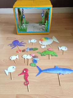 an assortment of sea animals on sticks in front of a box with water and sand