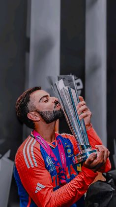 a man with a beard holding up a trophy in front of his face and looking to the side