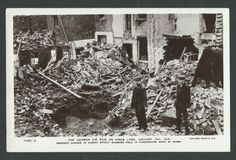 an old black and white photo of two men standing in front of a pile of rubble