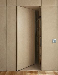 an open door in the middle of a room with wooden flooring and beige walls