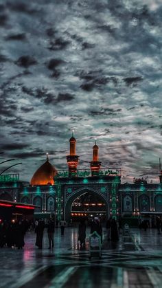 people are standing in front of an ornate building with domes and minarets at night