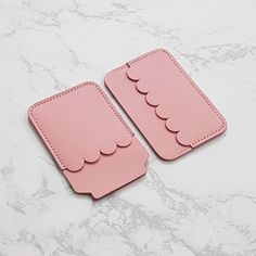 two pink coasters with scallops on them sitting on a marble countertop