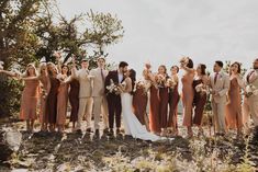 a group of people standing next to each other on top of a dirt field with trees in the background