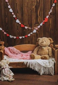 two teddy bears sitting on a wooden bed with hearts hanging from the wall behind them