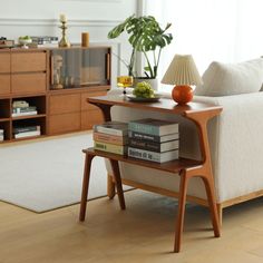 a living room with a white couch and wooden table in front of the sofa is filled with books