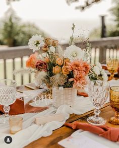 a wooden table topped with lots of flowers next to glasses and napkins on top of it