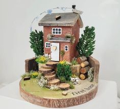 there is a small house made out of wood and plants on top of a tree stump